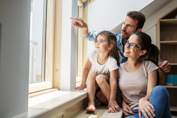 Portrait of young family.They sitting by the window in living ro AdobeStock_255750201_01.jpeg